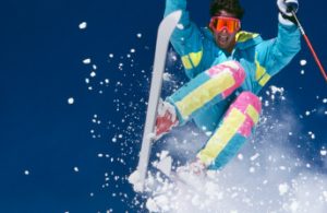 Snow Skier with Fresh Snow Jumping Towards Camera.
